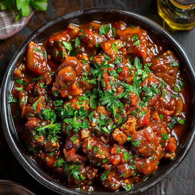 Close-up of vegetable manchurian showing golden-brown crispy cabbage-carrot balls drenched in shiny sticky soy-tomato-chili gravy, green chili rings, sesame seeds, fresh cilantro